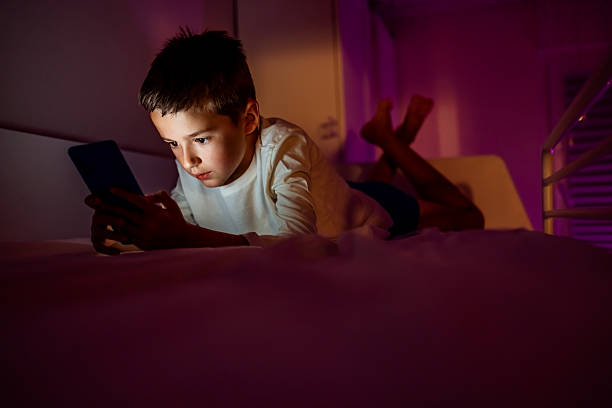 istock Young Child Absorbed in Using a Tablet in a Dimly Lit Room 2217270258