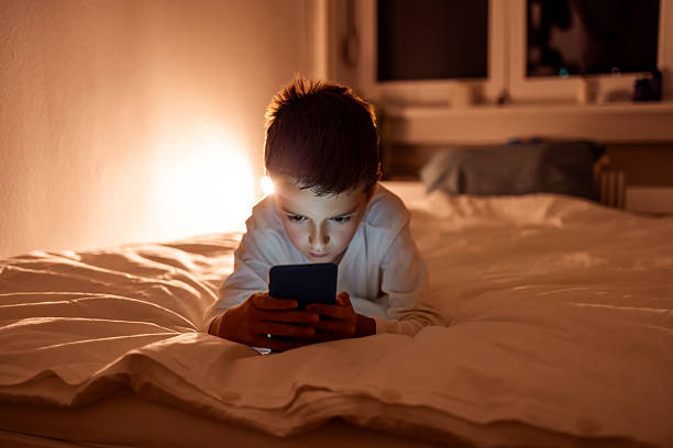 istock Boy Looking at Smartphone Screen in Bed During Evening 2217270276