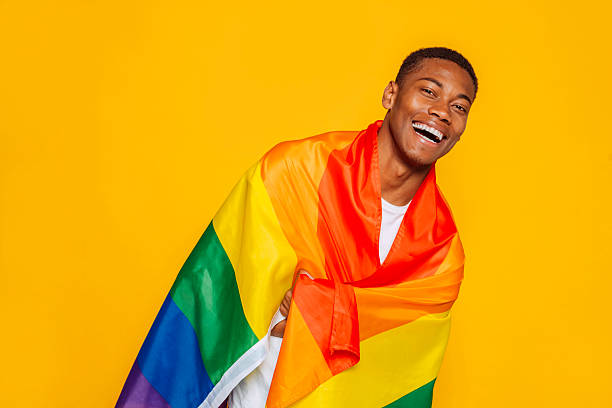 istock Young man laughing and wrapped in rainbow flag celebrating pride month 2217272325