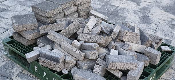 Broken and stacked concrete sidewalk blocks on green pallet. Used in pavement construction, urban landscaping, and road repair works.