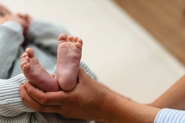 istock Tender Moment: Mother Holding Baby's Feet in Cozy Home Setting 2217274675