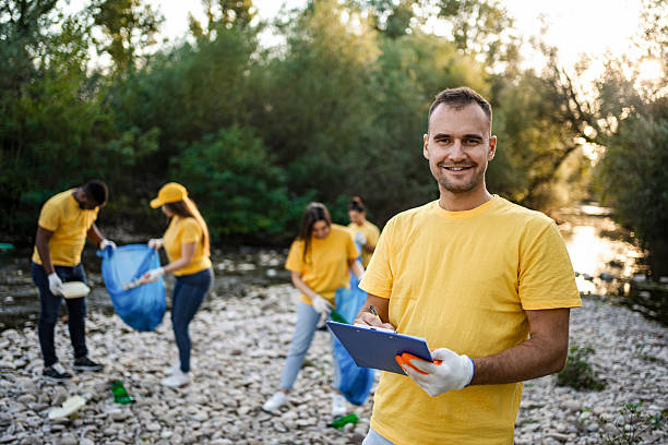 Volunteer taking notes while other volunteers are collecting garbage in the river