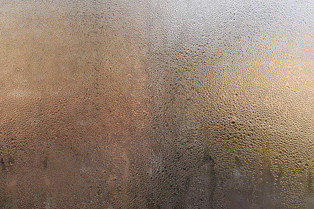 istock natural condensation forming on cold glass surface. water droplets, creating an abstract pattern. Cool atmosphere with transparent effect. drops on foggy window, blurring outside view. wet window. 2217277157