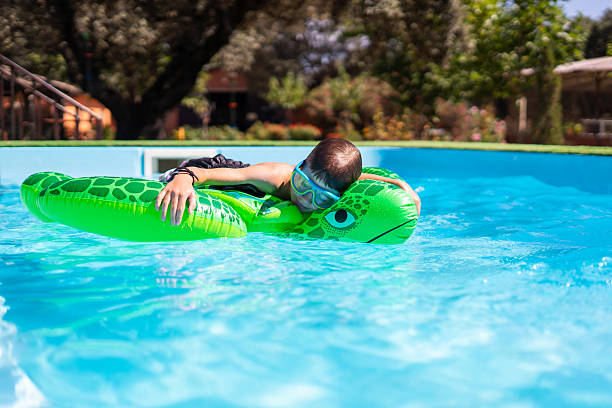 istock Boy relaxing on inflatable turtle in swimming pool during summer vacation 2217278283