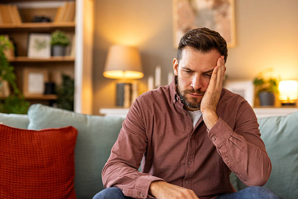 istock Closeup of man suffering from headache at home, touching his temples, copy space, blurred background. Migraine, headache, stress, tension problem, hangover concept 2217281160