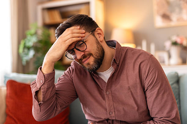 istock Closeup of man suffering from headache at home, touching his temples, copy space, blurred background. Migraine, headache, stress, tension problem, hangover concept 2217281177