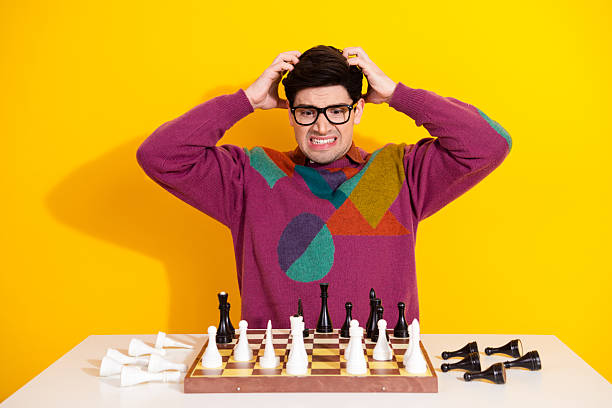 istock Frustrated Young Man in Bright Sweater Expressing Stress Over Chess Game on Yellow Background 2217282474