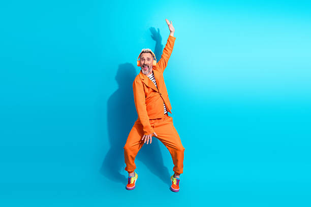istock Cheerful gentleman in vibrant orange suit gesturing energetically against a bright blue background 2217284393