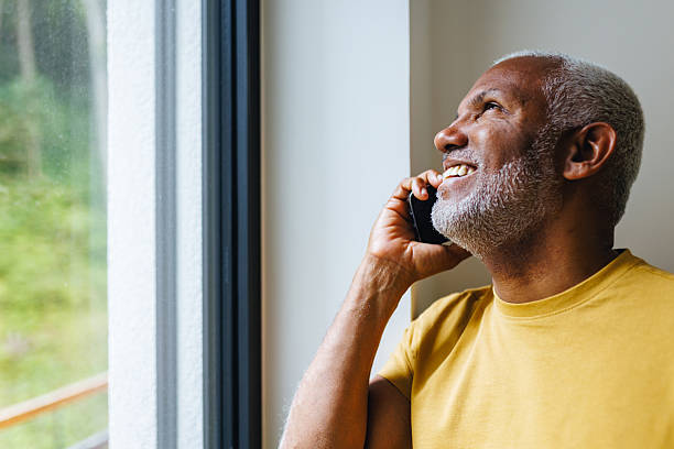 istock Portrait of Happy Man Using Mobile Phone by Window 2217286112