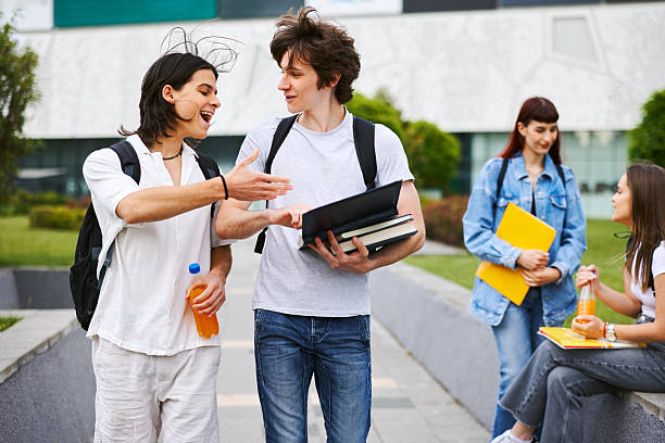 two young women smiling happy while walking down a sidewalk with backpack and folder, concept of students and urban youth lifestyle, copy space for text