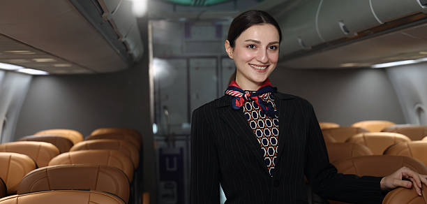 istock Flight attendant or Air Hostess. A friendly flight attendant stand confidently inside an airplane cabin. Professional hospitality and elegant uniform. Aviation service travel airline Flight attendant. 2217287519