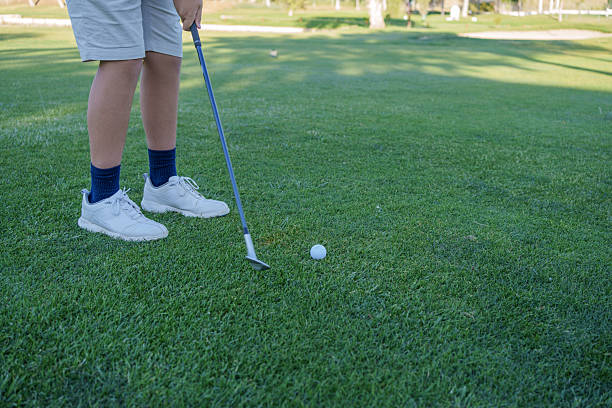 istock Young golfer hitting a golf ball on a green golf course 2217289635