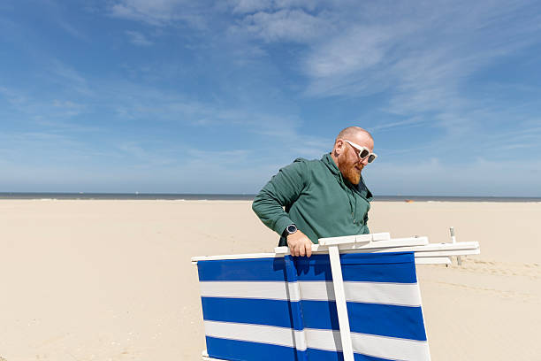 Handsome senior male tourist enjoying a walk on a beach whilst on a coastal vacation in Scheveningen, the Netherlands