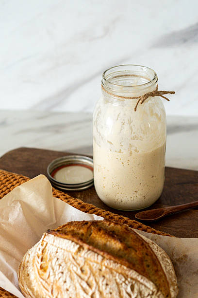 istock Freshly baked sourdough bread with a jar of starter and rustic cloth 2217291902