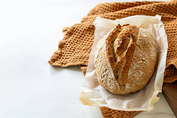 istock Freshly baked sourdough bread with a jar of starter and rustic cloth 2217291945