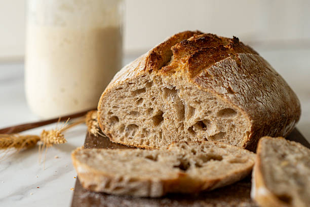istock Freshly baked sourdough bread with a jar of starter and rustic cloth 2217292190