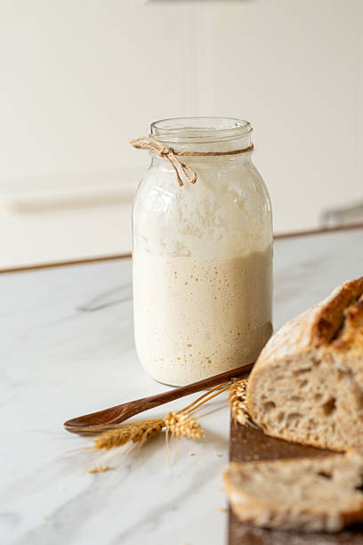 istock Freshly baked sourdough bread with a jar of starter and rustic cloth 2217292220