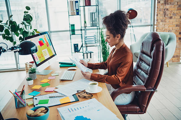istock Young professional businesswoman reviewing documents at her modern office workspace with contemporary decor and natural lighting 2217292286
