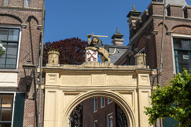 The iconic entrance to the Burcht van Leiden in the Netherlands, featuring a magnificent archway crowned with a historic lion sculpture and coats of arms under a bright blue sky