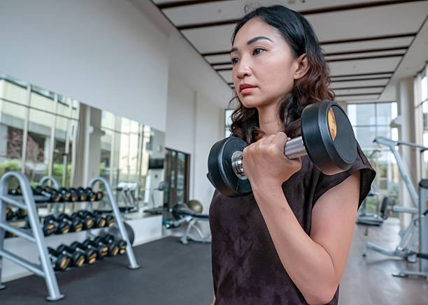 istock Asian Woman Lifting Dumbbell for Upper Body Training 2217292575