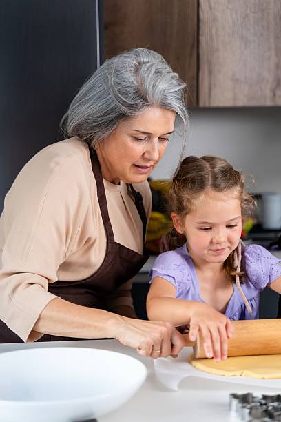 istock Grandmother teaching granddaughter how to roll dough in kitchen 2217294165