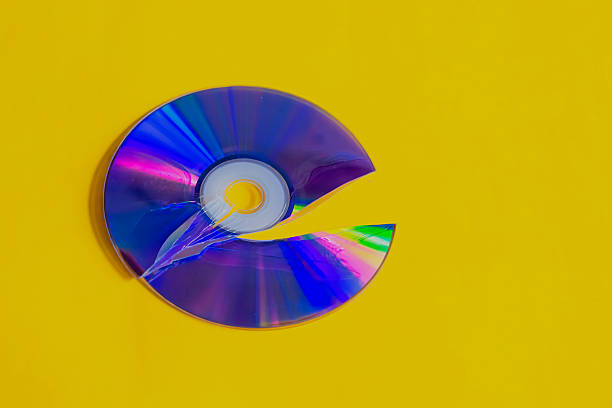 A broken disc on a bright yellow background, a cracked CD disc, damage to an old storage medium, retro technology from past years.