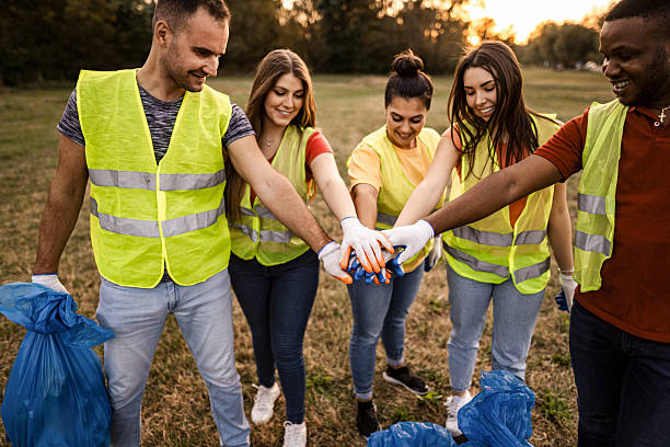 istock Volunteers joining hands before collecting garbage in a public park 2217297128