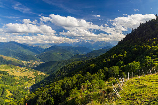 Stunning view of the Pyrenees mountains in France, showcasing lush valleys, distant peaks, and a vibrant blue sky with fluffy white clouds