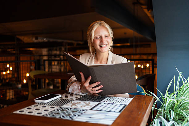 istock Young woman smiling and reading menu in restaurant 2217303027