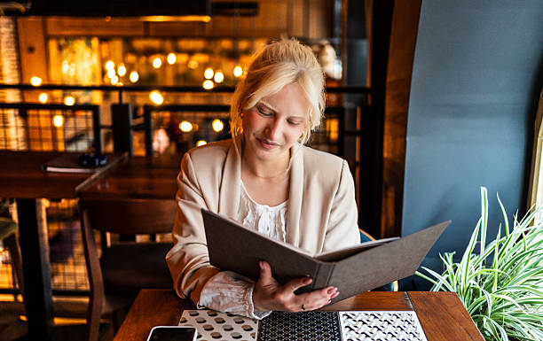 istock Young businesswoman reading menu in restaurant, making a decision 2217304210