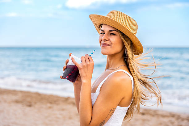 istock Young woman enjoying a refreshing drink on the beach 2217306182
