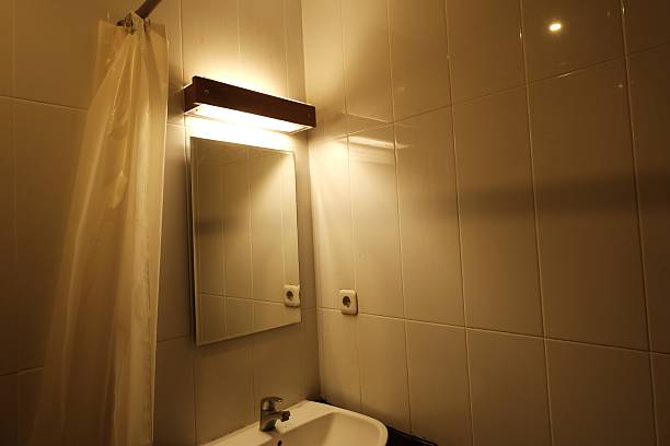 istock Minimalist bathroom corner featuring a white ceramic sink, wall-mounted mirror, and soft ambient lighting, set against clean white tiled walls 2217314335