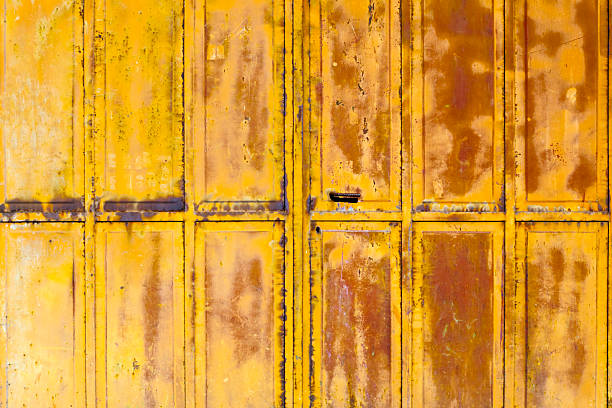 Old yellow closed door , keyhole and handle, paint peeling off, copy space available Galicia, Spain. Suitable for backgrounds purposes.