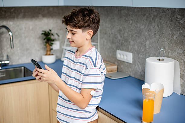 istock Young boy managing type 1 diabetes while interacting with technology in a domestic kitchen setting 2217317952