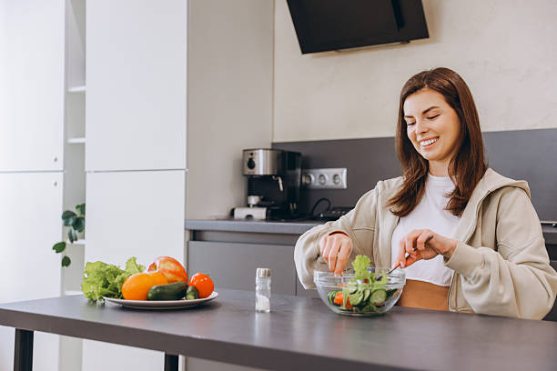 istock Young Woman Preparing a Fresh Salad in Modern Kitchen 2217321342