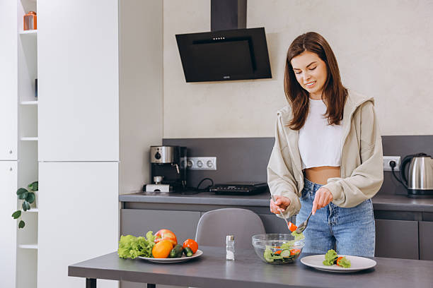 istock Young Woman Preparing a Fresh Salad in Modern Kitchen 2217321422