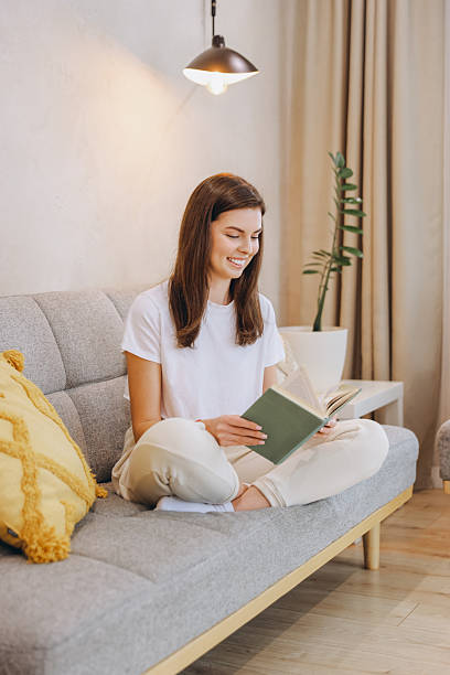 istock Young Woman Reading a Book at Home on the Sofa 2217321913