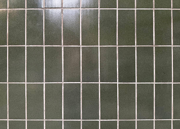 istock This close-up shot showcases a grid of dark green, vertically-oriented rectangular tiles with light gray grout lines, creating a clean and somewhat industrial or modern aesthetic. 2217322007