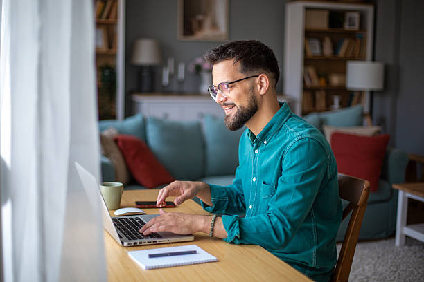 istock Young adult man working from home, using laptop computer 2217323680