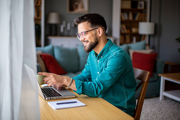 istock Young man working from home on laptop and smiling 2217323730