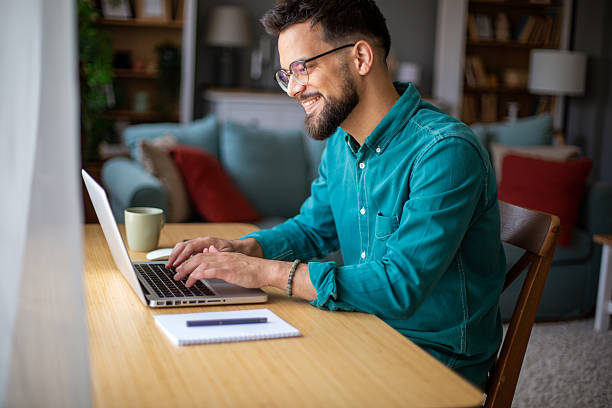 istock Happy young man working from home, typing on his laptop and smiling 2217323770
