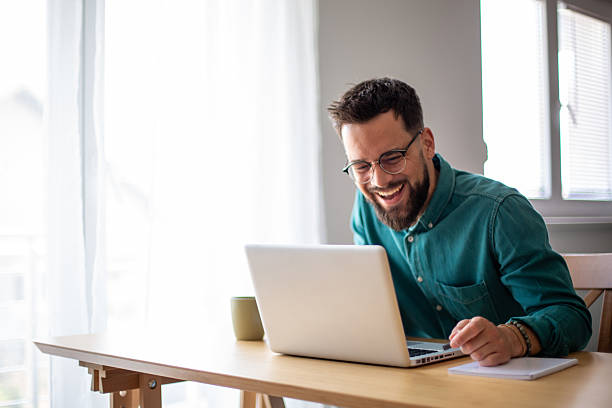 istock Young businessman laughing while working on his laptop at home 2217324466