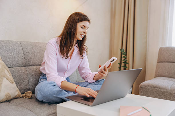 istock Young Woman Working From Home Using Laptop and Smartphone 2217324636
