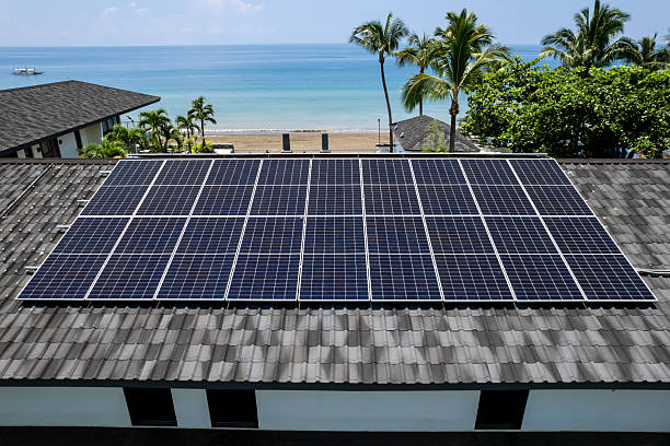 istock An array of Solar panels mounted on a resort building rooftop, with a beautiful tropical beach and palm trees in the background. At Real, Quezon, Philippines. 2217325846
