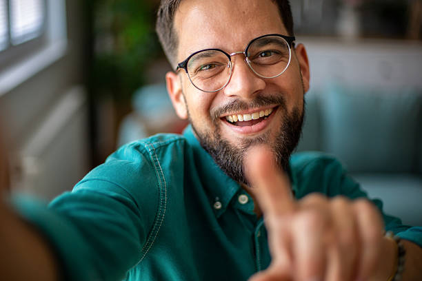 istock Smiling young man taking a selfie and pointing at the camera 2217326088