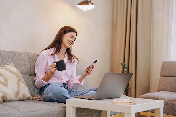 istock Young Woman Working Remotely from Home, Enjoying Coffee and Using Smartphone 2217326630
