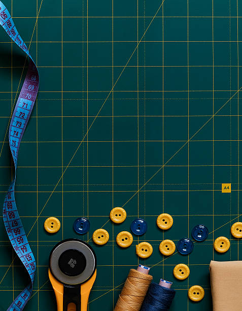 istock Sewing accessories on a green cutting mat. Buttons, threads. cloth, meashuring tape, zippers, roller cutter and scissors. Top view. Copy space. 2217329249