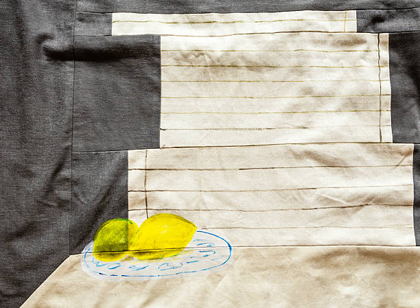 fragment of handcrafted textile panno with handpainted yellow lemons on plate at table