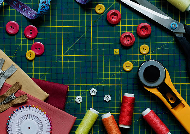 istock Sewing accessories on a green cutting mat. Buttons, threads. cloth, meashuring tape, zippers, roller cutter and scissors. Top view. Copy space. 2217330033