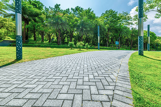 istock Stone brick pathway winding through a verdant city park with lush trees on a bright sunny day. 2217333054